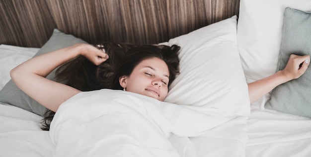 Premium Photo | A young woman laying in bed and awake in morning ...