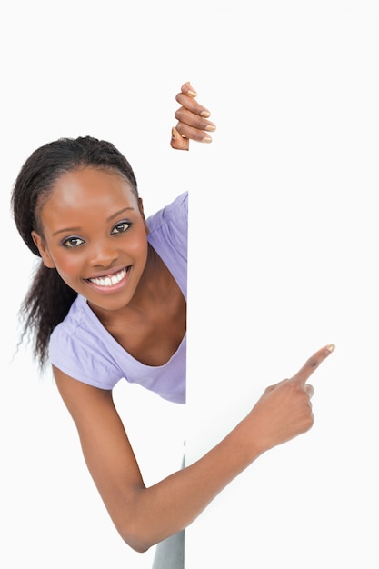 Premium Photo Young Woman Looking Around The Corner Pointing At Something On W