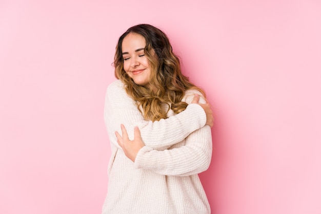 Young woman posing in a pink wall isolated hugs, smiling carefree and happy Premium Photo