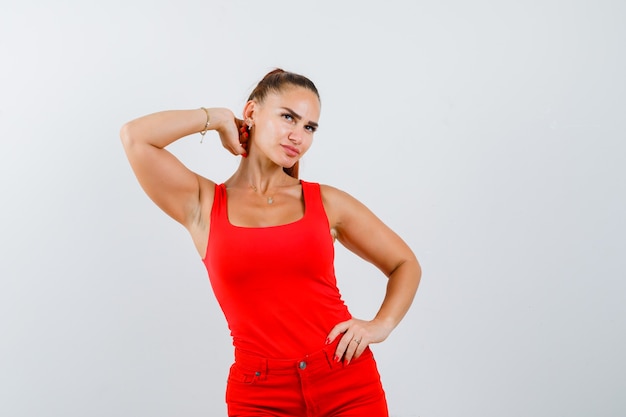 Free Photo | Young woman in red tank top, pants holding hand on neck ...