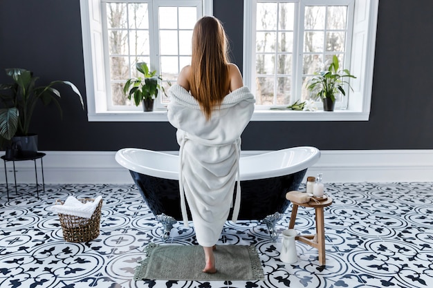 Premium Photo | Young woman removes her white robe while standing at ...