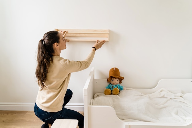 Young Woman Renovation Child Room In New House Wooden Bookshelf