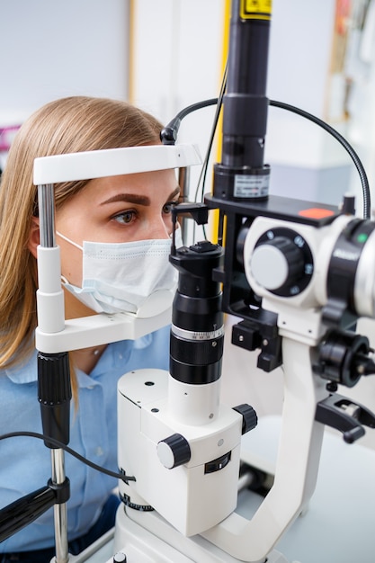 Premium Photo | Young woman sitting in armchair looking at slit lamp ...