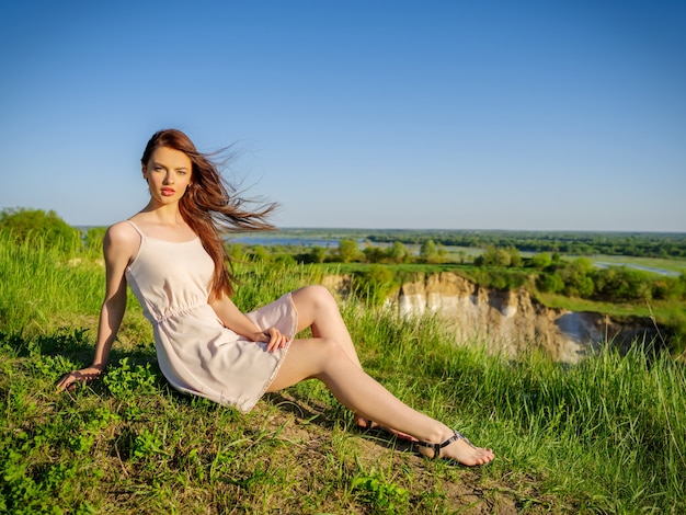 Free Photo | Young woman sitting by a cliff outdoors on nature