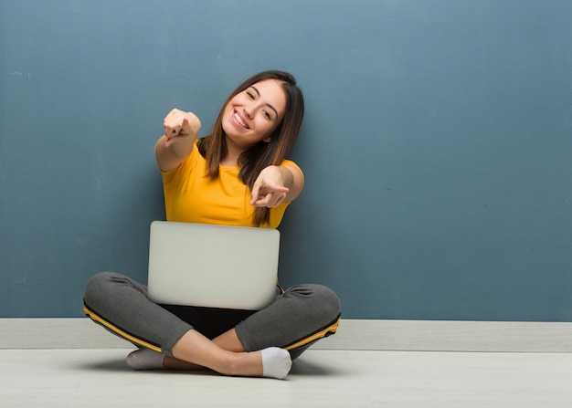 Premium Photo Young Woman Sitting On The Floor With A Laptop Cheerful And Smiling Pointing To