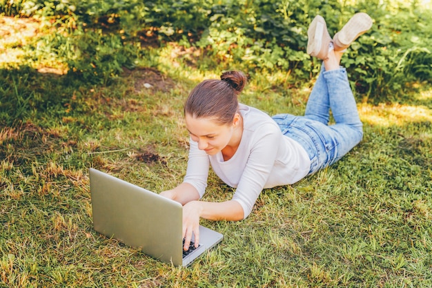 Premium Photo | Young woman sitting on green grass with her laptop