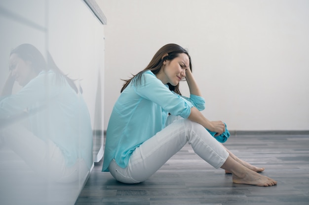 Premium Photo | Young woman sitting on kitchen floor holding her head ...