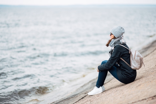 Young woman sitting near the beach on a windy weather | Premium Photo