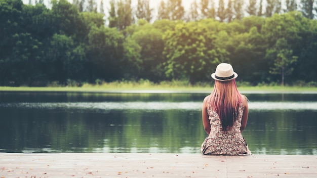 Free Photo | Young woman sitting on pier and looking at the river.