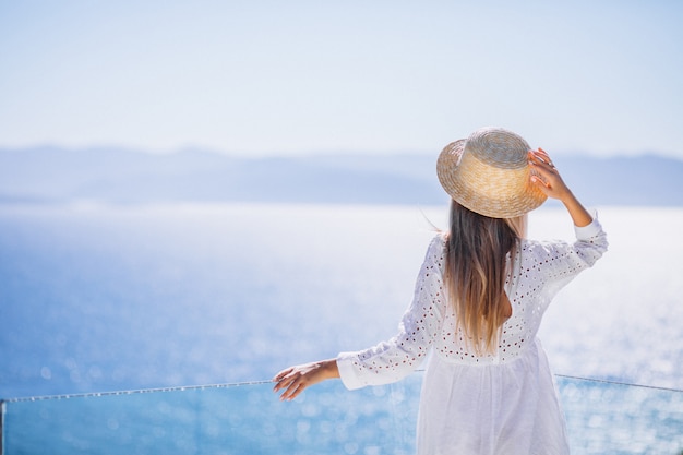Young woman standing from the back and looking at the sea 