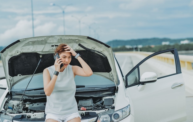 Premium Photo Young Woman Standing Near Broken Down Car With Popped Up Hood Having Trouble