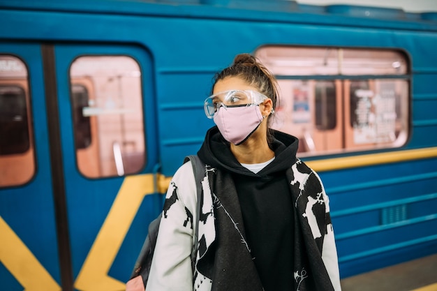 Young woman standing at station in medical protective mask Free Photo