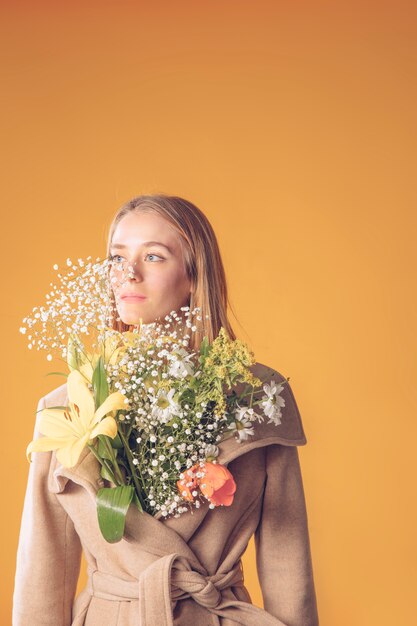 Free Photo | Young woman standing with flowers bouquet in coat