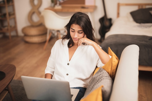 Young woman staying on sofa and working on laptop Free Photo