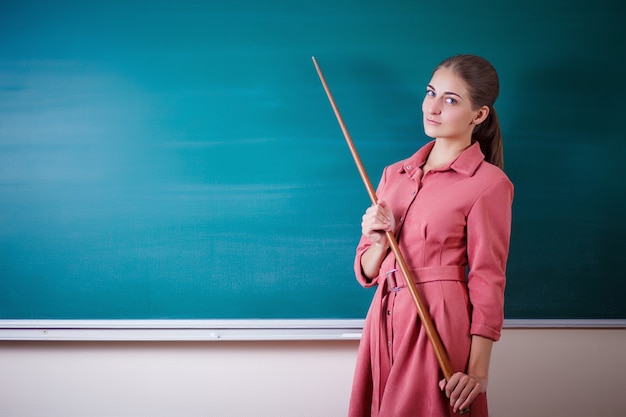 Premium Photo Young Woman Teacher Stands At A Blackboard With A Pointer Teachers Day 2159