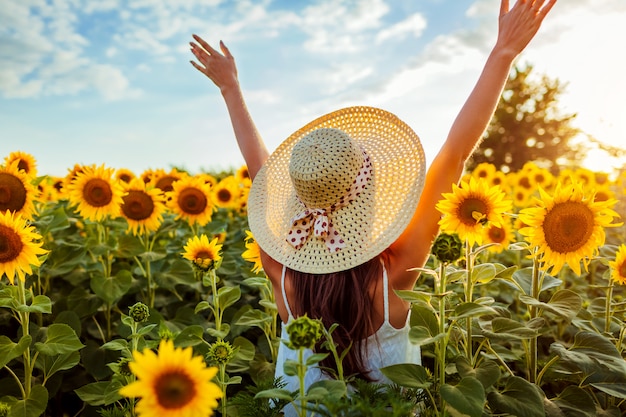 Premium Photo | Young woman walking in blooming sunflower field raising ...