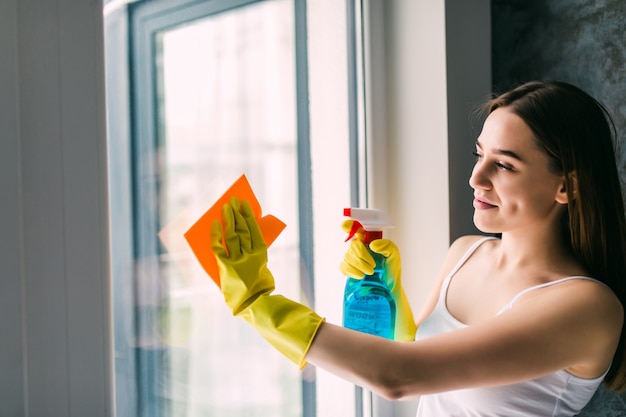 Young woman washing window Free Photo