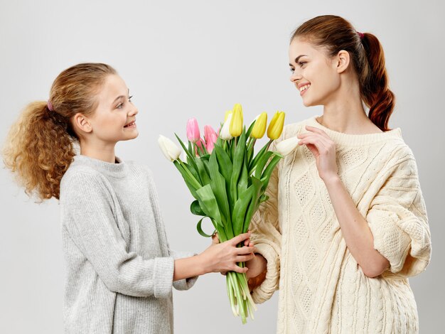 花とスタジオでポーズをとる子供を持つ若い女性 プレミアム写真
