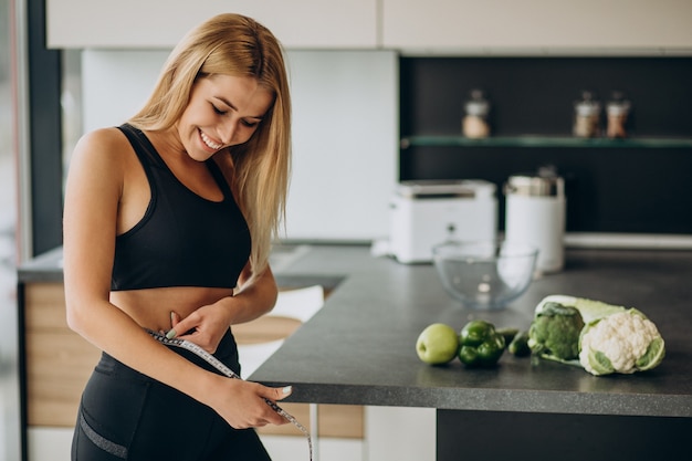 Young woman with measuting tape on weist at the kitchen Free Photo