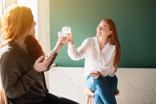 若い女性がカフェで話しています コーヒーを飲みながら笑顔の女性モデル プレミアム写真