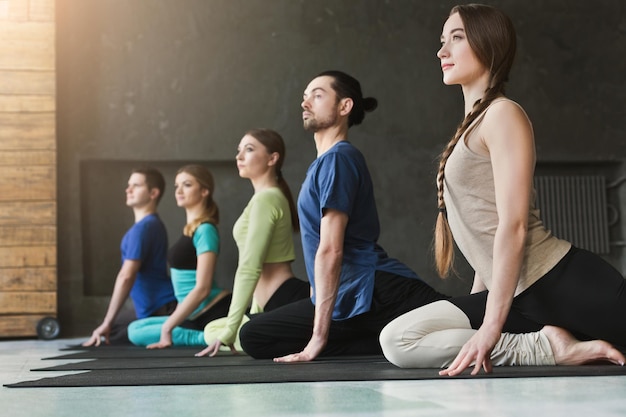 Premium Photo | Young women and men in yoga class, meditation exercises ...