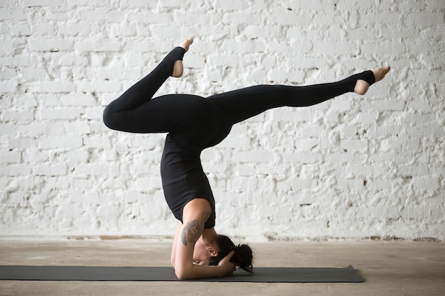 Young yogi attractive woman doing supported headstand pose varia Photo ...