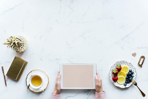 Aerial view of woman using a digital tablet on a marble table with design space Free Psd Aerial view of woman using a digital tablet on a marble table with design space Free Psd