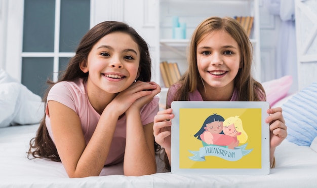 Best friends smiling while looking at the camera with tablet mock-up Free Psd