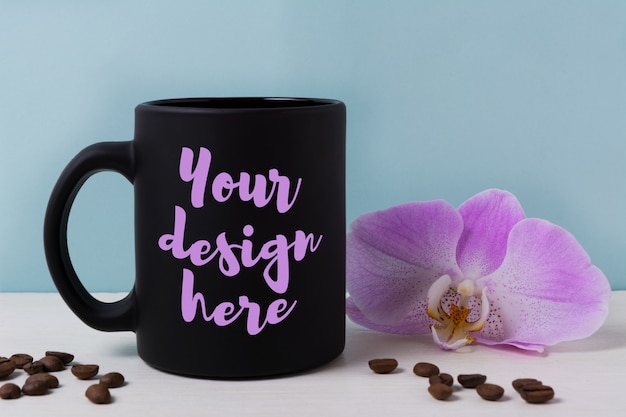 Download Black mug mockup with orchid and coffee beans | Premium PSD File