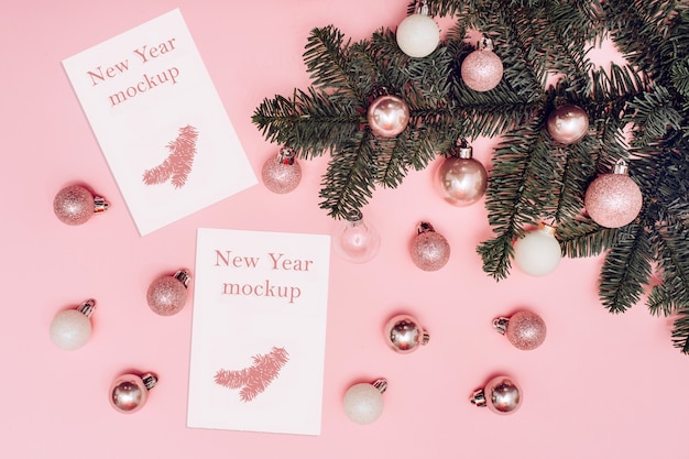 クリスマスのモックアップ ピンクの背景に白とピンクのボール テキスト用の白いカードとスプルースの枝 プレミアムpsdファイル