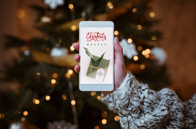 Download Christmas sale mockup with hand holding smartphone | Free PSD File