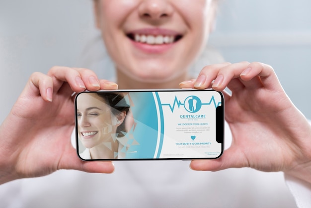 Download Close-up dentist holding a smartphone mock-up | Free PSD File