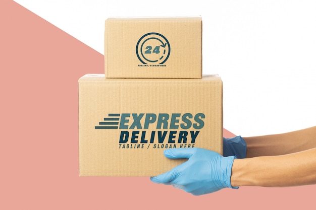 Closeup delivery man hand in medical gloves holding cardboard box mockup template. Premium Psd