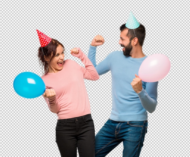 Couple with balloons and birthday hats celebrating a victory in winner position | Premium PSD File