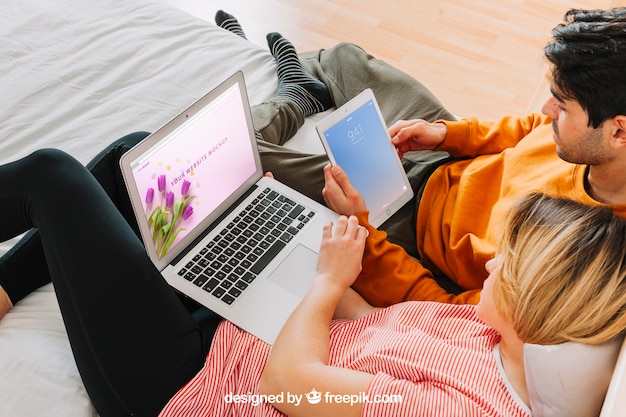 Couple with laptop and tablet in bed PSD Template