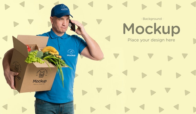 Download Free PSD | Delivery man holding a box with vegetables mock-up