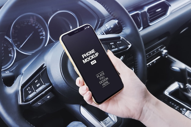 Download Premium PSD | Hand holding smartphone in car scene mockup