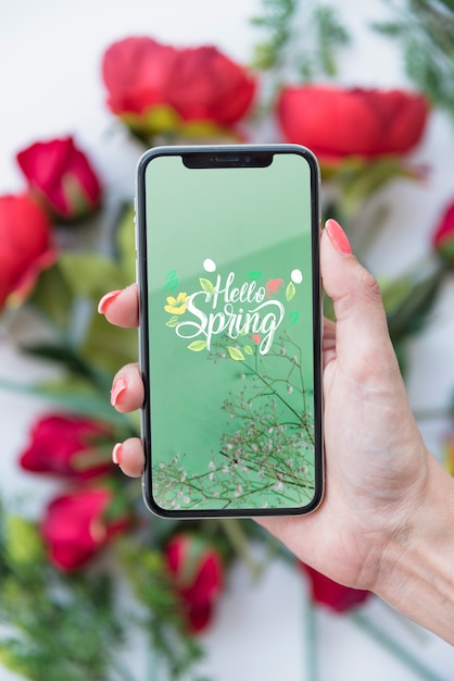Download Hand holding smartphone mockup above flowers | Free PSD File