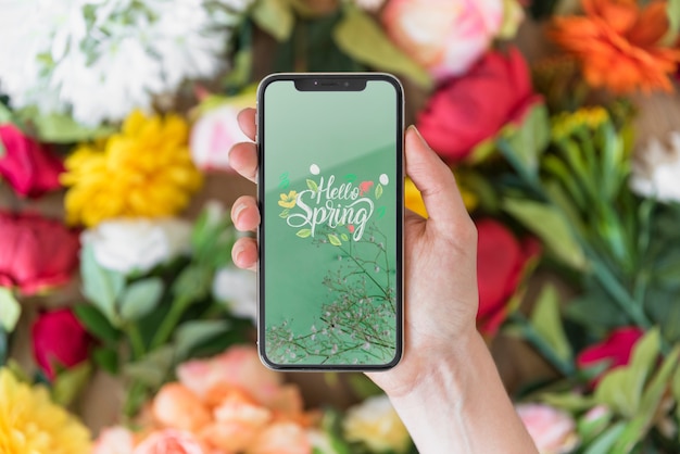 Download Hand holding smartphone mockup above flowers | Free PSD File