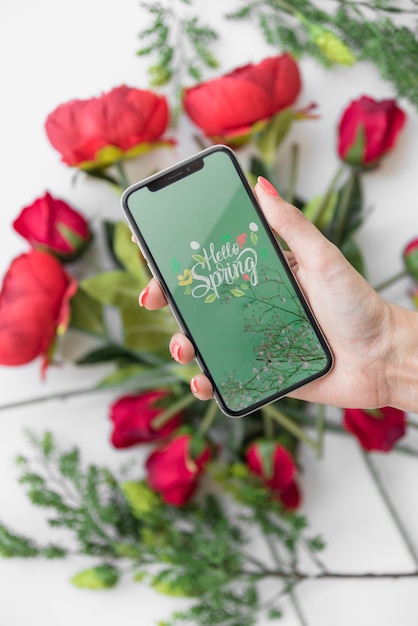 Download Hand holding smartphone mockup above flowers | Free PSD File