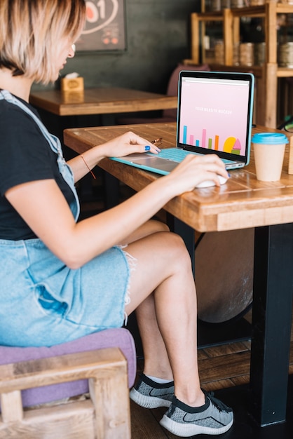 Download Laptop mockup with woman on wooden table | Free PSD File