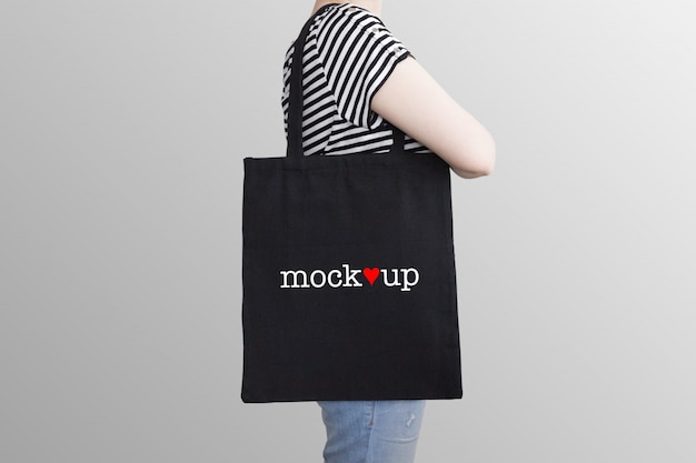 Mockup of a black tote bag on a model | Premium PSD File