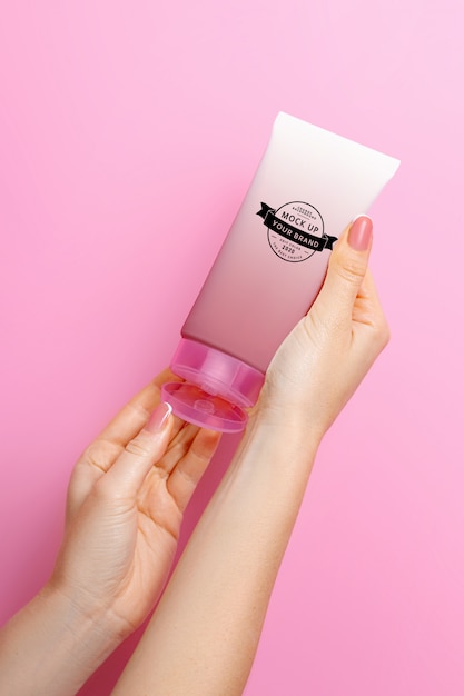 Mockup tube of cream in hands on a pink space | Premium PSD File