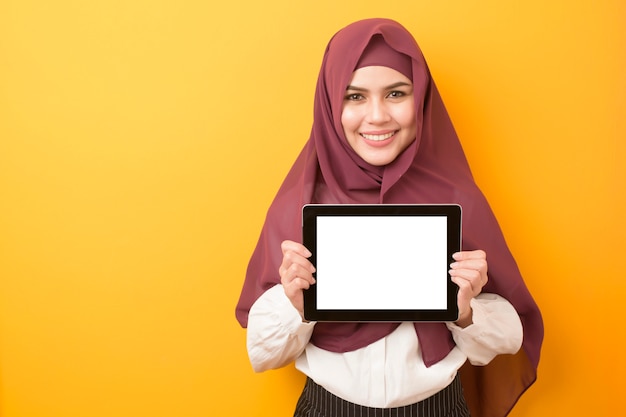 Portrait of beautiful university student is wearing hijab with tablet mockup on yellow ...