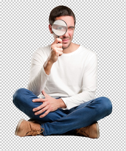 Download Seated pensive young man using a magnifying glass | Premium PSD File