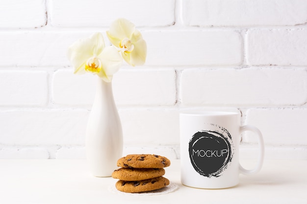 Download White coffee mug mockup with soft yellow orchid in vase and cookies | Premium PSD File