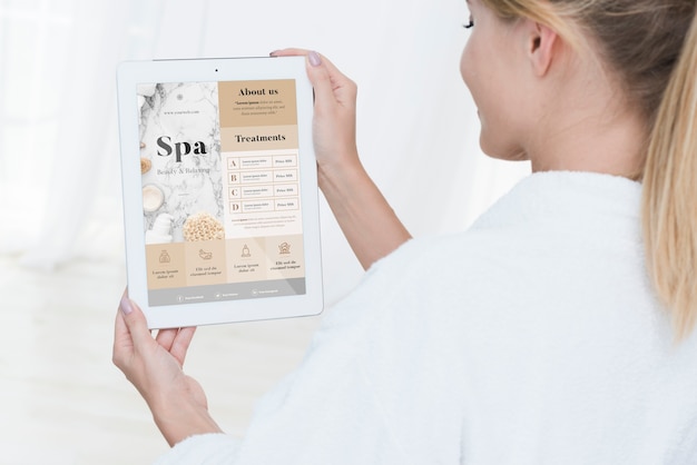 Woman holding tablet mock-up with spa offers | Free PSD File