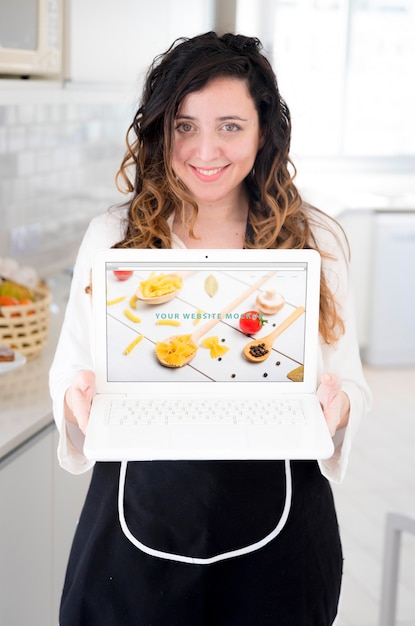 Free PSD | Woman in kitchen presenting laptop mockup