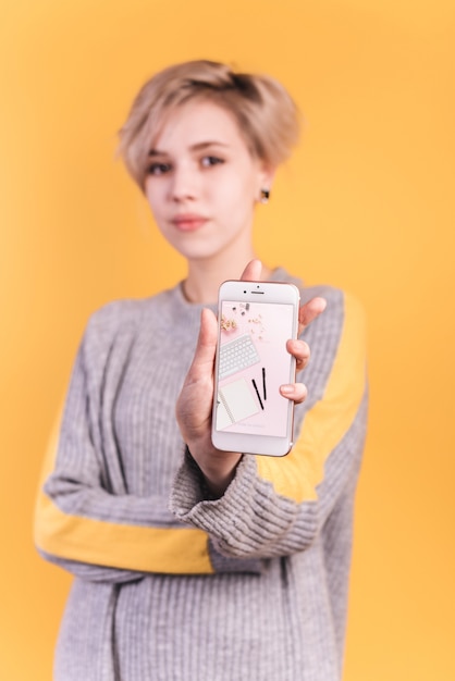 Download Young woman holding smartphone mockup | Free PSD File