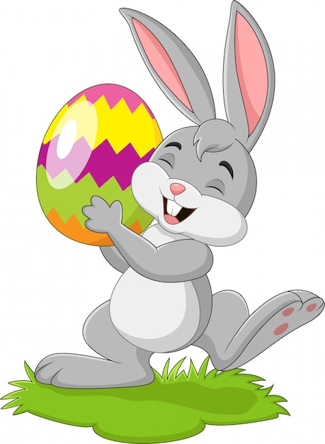 Premium Vector | Cartoon little rabbit holding easter egg in the grass